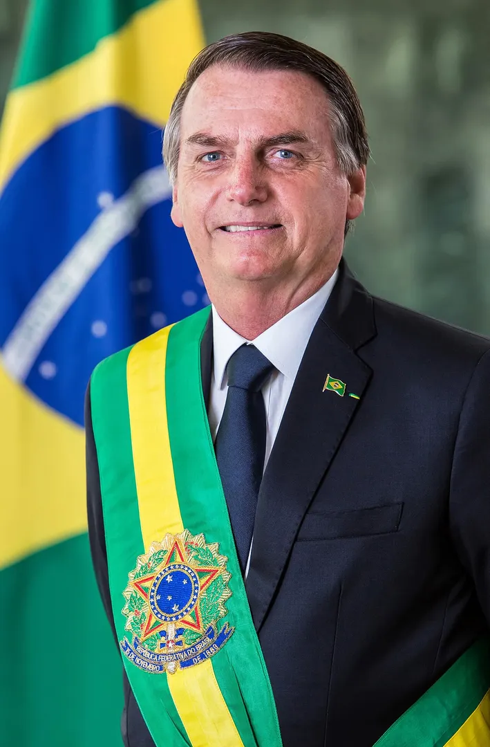 Retrato oficial de Jair Bolsonaro con la banda presidencial verde y amarilla y la bandera de Brasil detrás